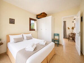 Ein Hotelzimmer mit Bett, Schrank, Stuhl und Schreibtisch mit Lampe.