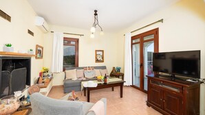 A cozy living room with a fireplace, sofa, television, and a dining area.