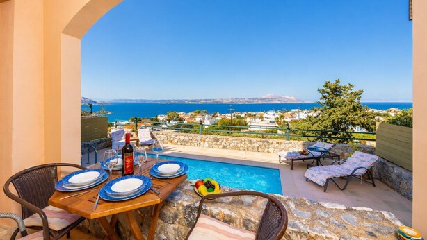 Ein Balkon mit Pool, Esstisch, Stühlen und Blick auf das Meer und die Stadt.