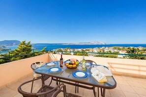 Une table dressée pour deux personnes, avec vue sur la mer et une ville côtière.