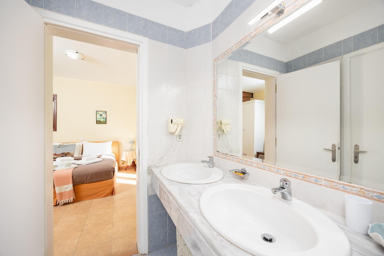 Une salle de bain d’hôtel avec deux lavabos, un grand miroir et un espace douche.