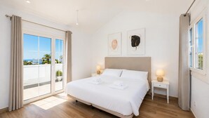A bedroom with a large bed, two bedside tables, a view through a sliding glass door, and artwork on the wall. - Villa Yaiza Secret 3 (Yaiza)