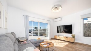 A modern living room with a grey sofa, a wooden coffee table, and a TV on the wall. - Villa Yaiza Secret 3 (Yaiza)