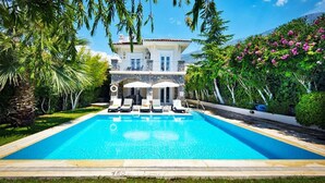 A poolside view of a two-story house with a clear blue pool, surrounded by lush greenery and a mountain in the background. - Villa Tara - Three Bedroom Villa, Sleeps 6 (Oludeniz)