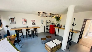 A modern kitchen with a bar area, wooden stools, and a red refrigerator. - Music Guest House (Mexico City)
