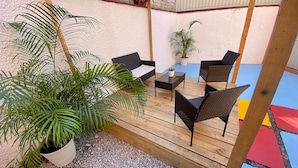 An outdoor patio with wooden flooring, wicker furniture, and potted plants. - Music Guest House (Mexico City)