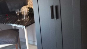 Ein Zimmer mit einem dunklen Wandschrank, einem kleinen Tisch mit Blumen und einem Stuhl.