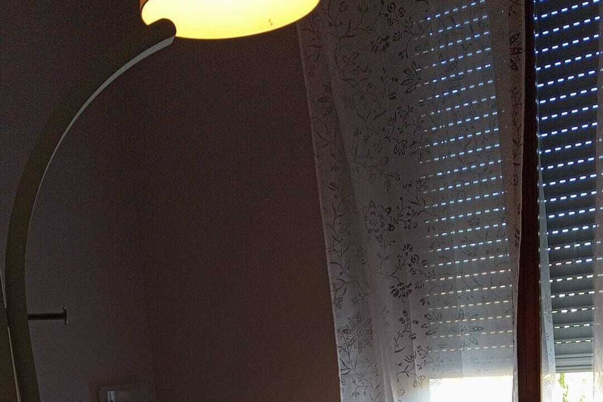 A bedroom with a bed, a lamp, and a window with a view.