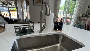 A kitchen with a stainless steel sink, a dish rack, and two bottles labeled "DISHES" and "HANDS". - 5BR Greeley Home - Sleeps 14, Pets Ok, EV Charger (Greeley)