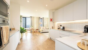 Una cocina moderna con armarios blancos, horno empotrado y un comedor con mesa y sillas.