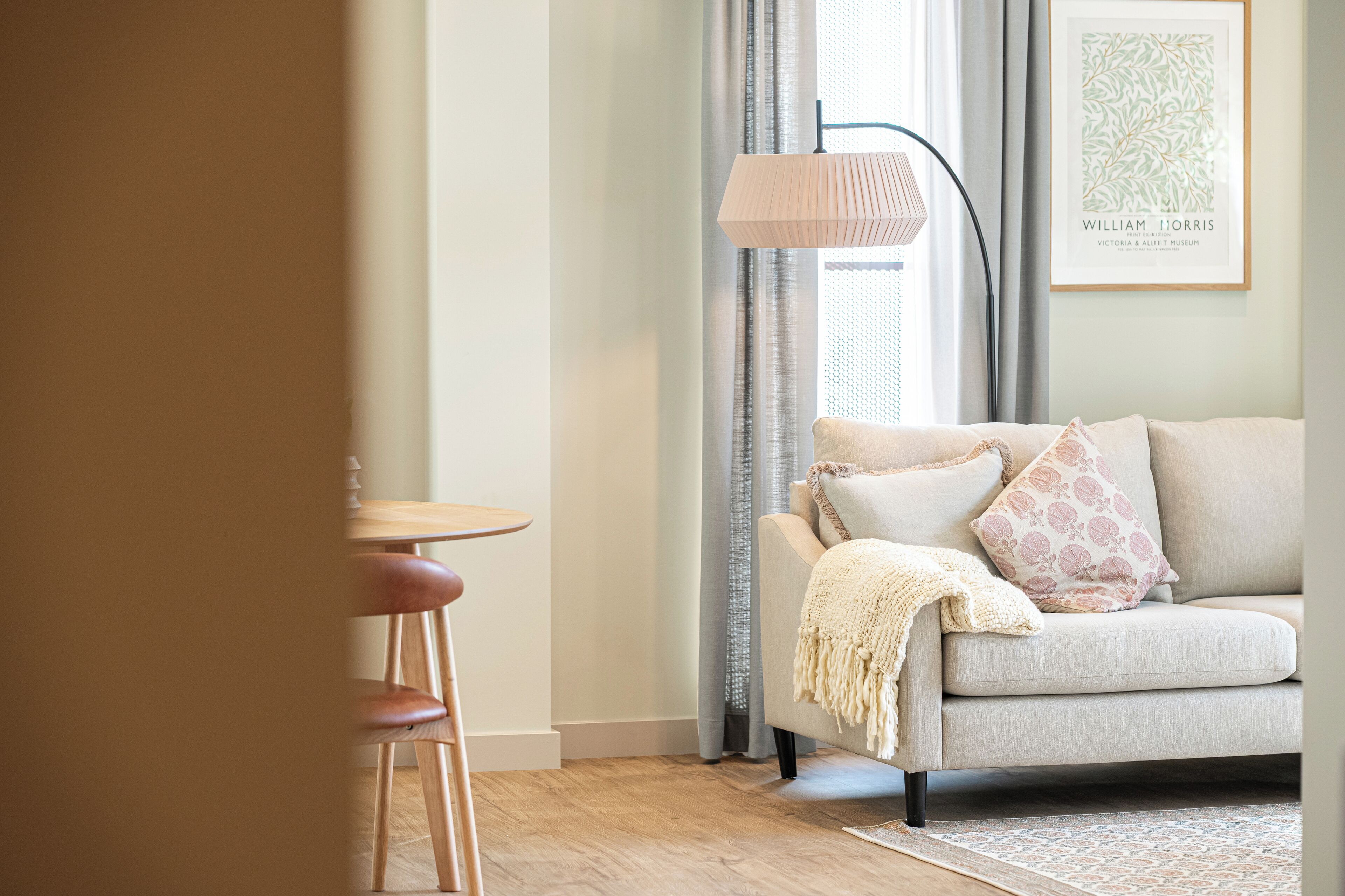 A living room with a sofa, a small table, a lamp, and a framed picture on the wall.