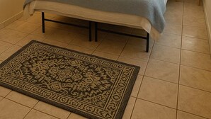 A bedroom with a bed, bedside lamps, a wall-mounted macrame piece, and a patterned rug. - Minutes to EVERYTHING! Gated home! AC in all rooms! (Hatillo)