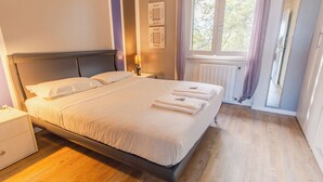 A neatly made bed with white linens and towels, a bedside lamp, and a window with curtains. - La Casa sulla Collina (Padenghe sul Garda)