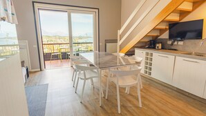 A modern kitchen with a dining area, a TV, and a view of the outdoors. - La Casa sulla Collina (Padenghe sul Garda)