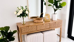 A wooden vanity with a large mirror, two potted plants, and a woven basket. - Beautiful Cape Coral Getaway with Sparkling Pool & Relaxing Outdoor Space! (Cape Coral)