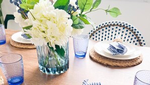 A dining table set with white plates, blue glassware, and a blue and white striped napkin. - Beautiful Cape Coral Getaway with Sparkling Pool & Relaxing Outdoor Space! (Cape Coral)