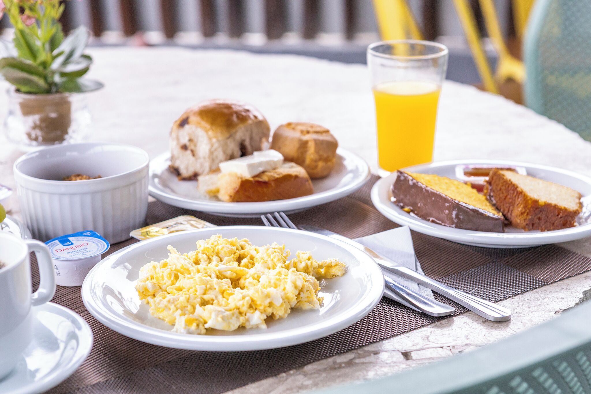 A breakfast setting with scrambled eggs, pastries, and a glass of orange juice on a table.