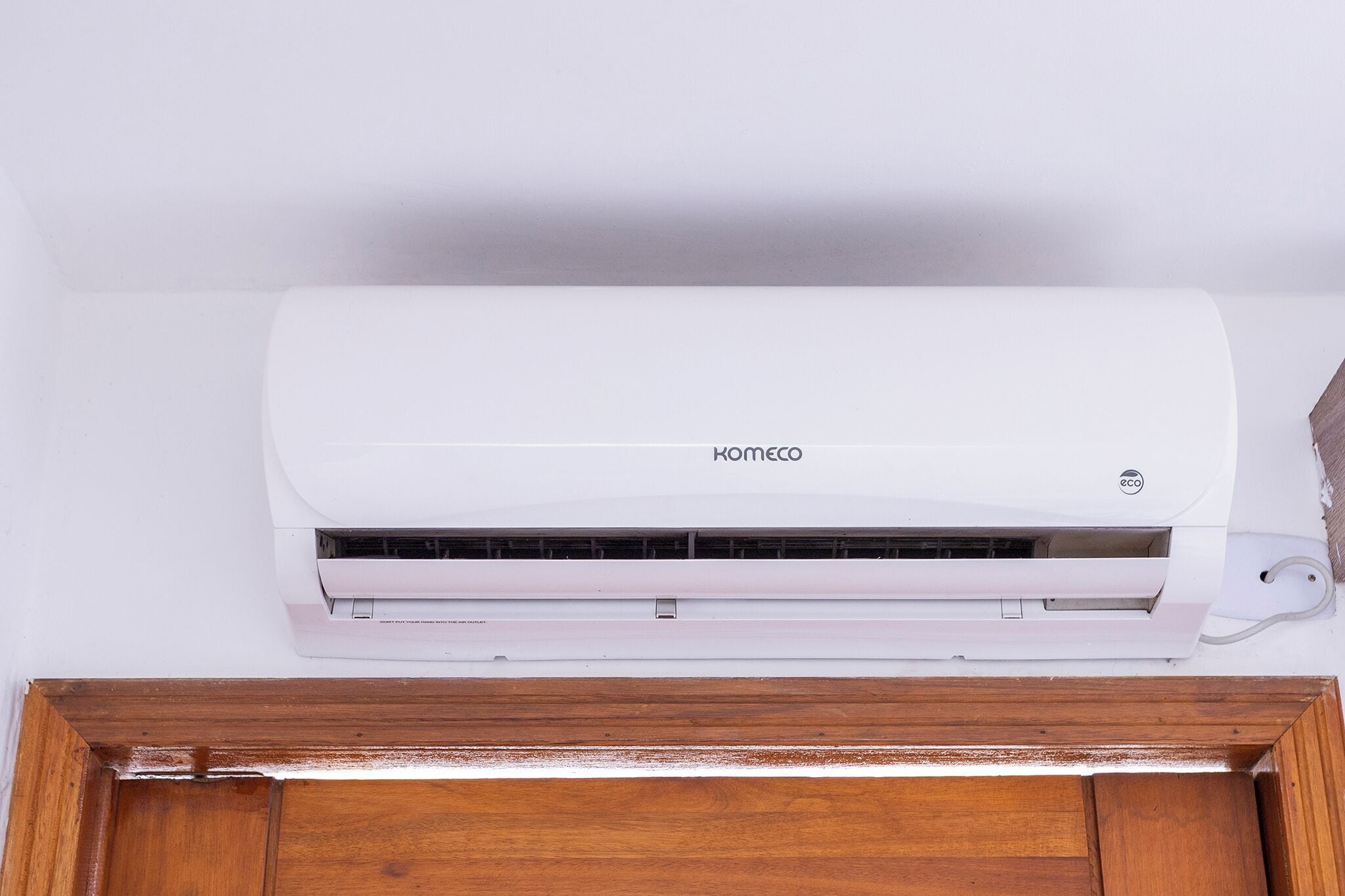 A white air conditioning unit mounted on a wall above a wooden cabinet.