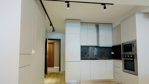 Una cucina moderna con mobili bianchi, una schiena di marmo nero e elettrodomestici in acciaio inossidabile.