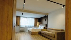 Una camera da letto moderna con un letto, una poltrona, pavimento in legno e una finestra con tende.