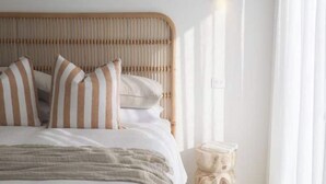 A bed with striped pillows, a wooden headboard, and a bedside table with a lamp. - Olas Villa 2 | Luxe 3BR · Plunge Pool · Near Beach (Anna Bay)
