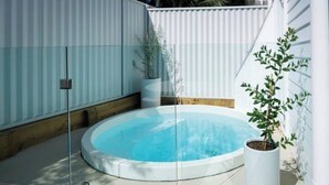 A circular hot tub surrounded by a glass enclosure, with a wooden deck and potted plants nearby. - Olas Villa 2 | Luxe 3BR · Plunge Pool · Near Beach (Anna Bay)