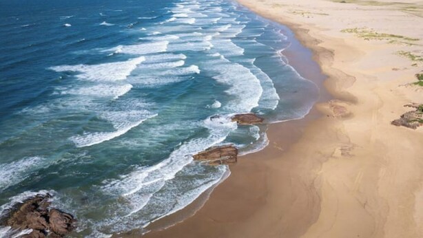Une plage où les vagues se brisent sur le rivage, une plage de sable et un ciel dégagé.