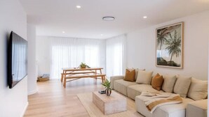 Un salon moderne avec un canapé, une table basse et un tableau accroché au mur.