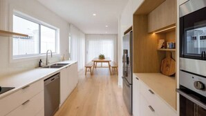 Une cuisine moderne dotée d’un îlot central, d’appareils électroménagers intégrés et d’un coin repas avec une table et des chaises.