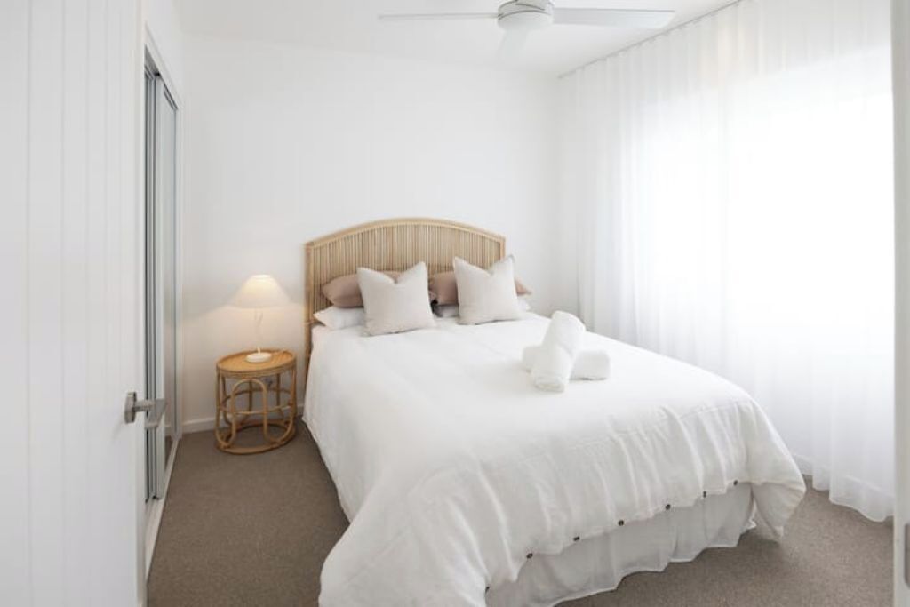 Ein ordentlich eingerichtetes Schlafzimmer mit Bett, Nachttischlampe und einem kleinen runden Tisch.