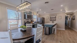 Una cocina moderna con una isla central, electrodomésticos de acero inoxidable y una lámpara colgante.