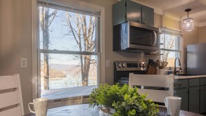 Una cocina con un ventanal grande, microondas y lavabo.