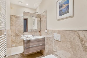 Une salle de bain moderne avec un lavabo en marbre, un grand miroir et une œuvre d’art encadrée accrochée au mur.