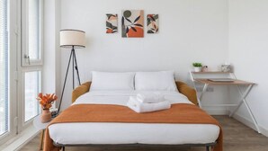 A modern bedroom with a bed, a desk, and a floor lamp. - Beautiful Flat • Prime Location • Balcony • Free Parking • Self-Check-In (Milton Keynes)