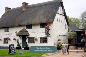 The Cross Keys, eine traditionelle Kneipe mit weißer Fassade, schwarzen Fensterläden und einem Strohdach.