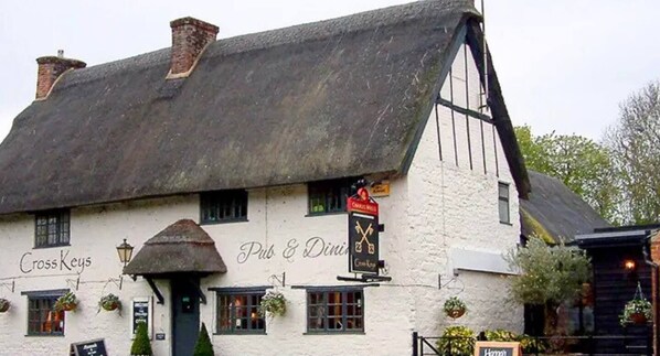 Le Cross Keys est un pub traditionnel à la façade blanche, aux volets noirs et au toit de chaume.