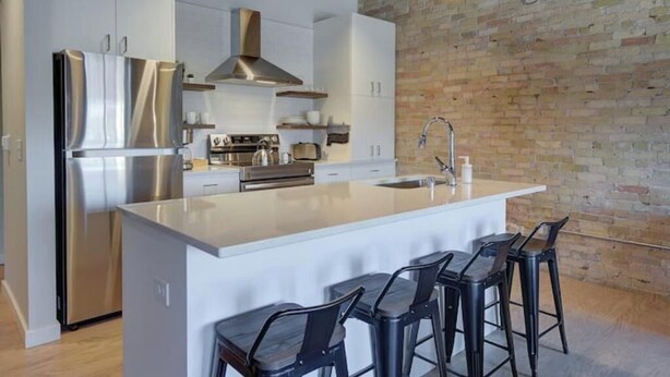Una cocina moderna con una isla grande, electrodomésticos de acero inoxidable y una pared de ladrillo.