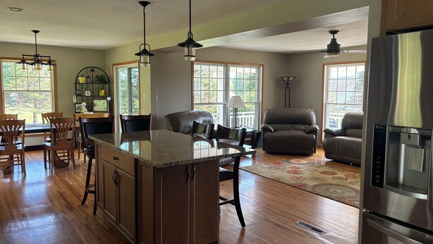 A spacious kitchen with a central island, wooden flooring, and large windows. - Peaceful country 5 bedroom home. Come make memories at your home away from home. (Poynette)