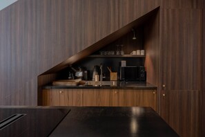 A modern kitchen with dark wood cabinetry, a black countertop, and stainless steel appliances.