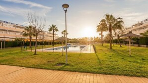 A pool area with a lamp post, palm trees, and a building in the background.