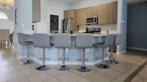 Eine moderne Küche mit Kochinsel, Barhocker und Holzschränken.