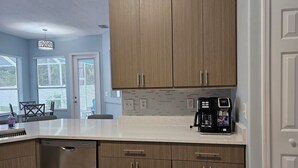Eine moderne Küche mit Holzausstattung, einer Kaffeemaschine und einem Geschirrspüler.