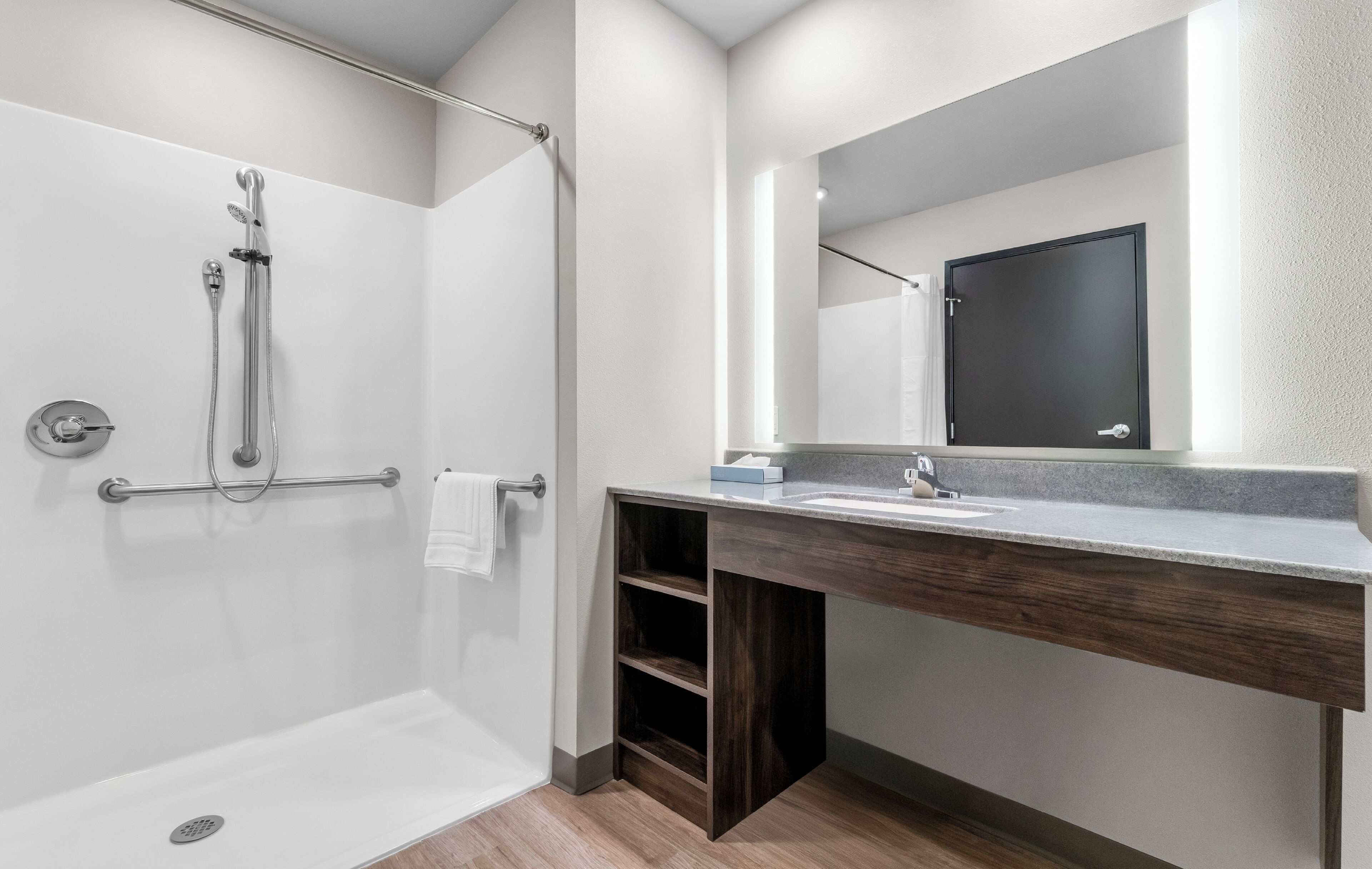 A modern bathroom with a shower, a sink, a mirror, and a towel rack.