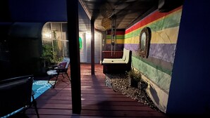 Un espacio al aire libre techado con cubierta de madera, una silla y un banco.