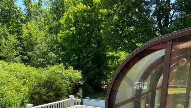 Una terraza con jacuzzi, mobiliario exterior y un espacio cerrado con vidrio.