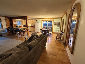 A spacious living room with a large sofa, a dining area with a wooden table and chairs, and a kitchen in the background. - JOLLY GREEN giant  3Bedroom house, center of beautiful Walla Walla Valley (College Place)