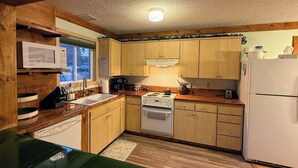 Una cocina compacta con armarios de madera, una estufa blanca, un microondas y un refrigerador.