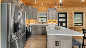 A modern kitchen with stainless steel appliances, wooden cabinets, and a central island. - Modern Rustic Log Cabin-Dog Friendly-Fenced-Views-Hot Tub (Morganton)