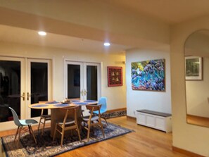 A dining area with a round table and chairs, a patterned rug, and a painting on the wall.