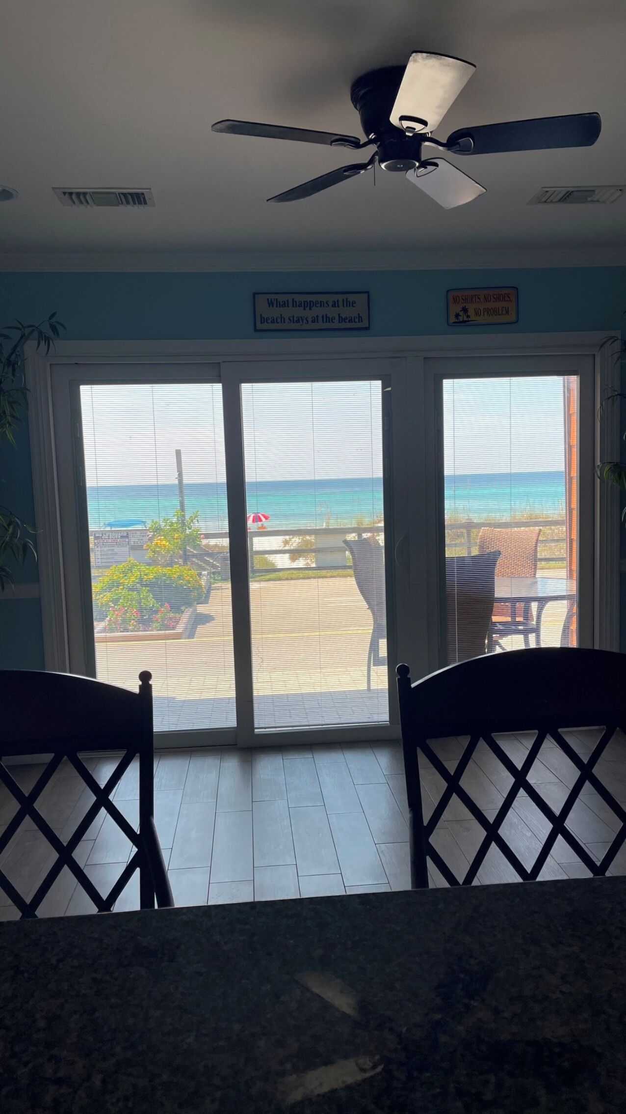Une chambre avec vue sur la plage, un ventilateur de plafond et un panneau accroché au mur.